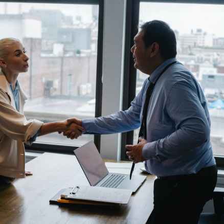 young woman shaking hands with boss after business presentation